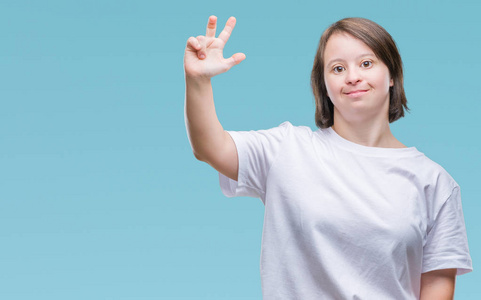 年轻的成年妇女患有唐氏综合症，在孤立的背景下，显示和举着三个手指，同时微笑，自信和快乐。