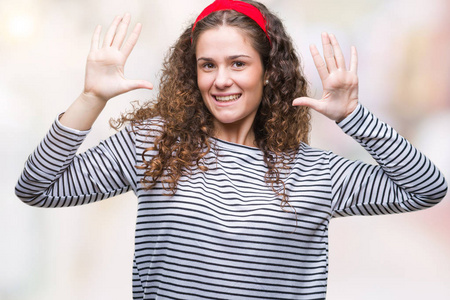 美丽的黑发卷曲的年轻女孩穿着条纹毛衣，在孤立的背景上，显示和指着10号手指，同时微笑自信和快乐。