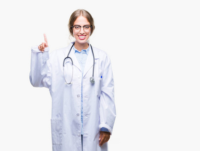 美丽的年轻金发医生女人穿着医疗制服，在孤立的背景上显示和指向第一手指，同时微笑自信和快乐。