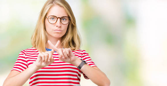 戴眼镜的漂亮年轻女子孤立的背景排斥表情交叉手指做负号