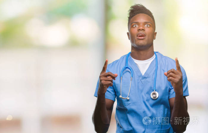 年轻的非裔美国医生，穿着外科医生制服的男人，惊讶地抬头，用手指和举起的手臂指着。