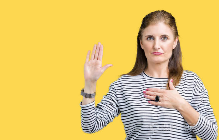 中年成熟美丽的女人穿着条纹冬衫,在孤立的背景下发誓,用手放在胸前