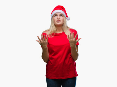 年轻的高加索女人戴着圣诞帽，在孤立的背景上疯狂疯狂地大喊大叫，咄咄逼人的表情和手臂抬起。 挫折概念。
