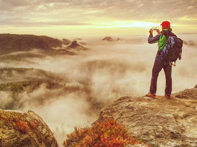 徒步旅行者博主用智能手机拍摄秋日山景。 分享旅行生活方式和冒险假期。 使用户外现代技术