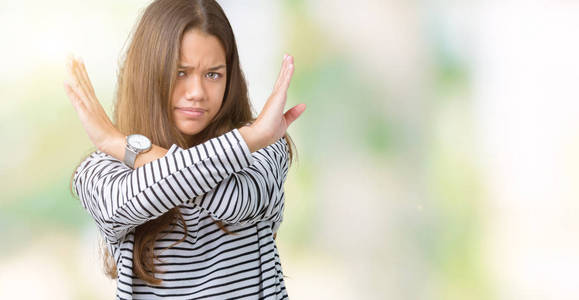 年轻漂亮的黑发女人,穿着条纹毛衣,背景排斥表情交叉手臂做否定标志