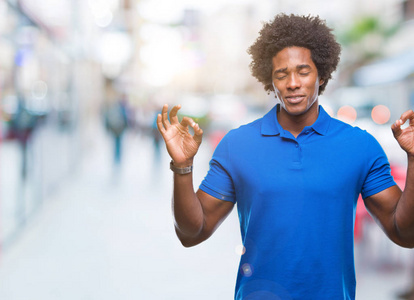 美国黑人男子在孤立的背景下放松和微笑，闭着眼睛做冥想手势与手指。 瑜伽概念。