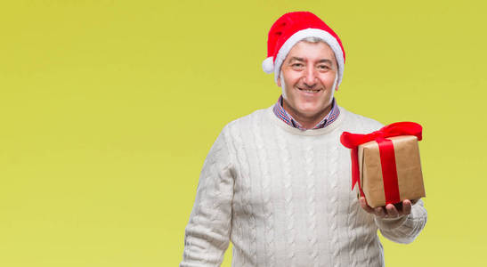 英俊的老人戴着圣诞帽，手里拿着礼物，脸上洋溢着幸福的笑容，露出自信的牙齿