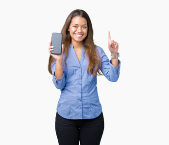 年轻漂亮的深色头发的商务女性展示智能手机屏幕，背景偏僻，惊讶于一个想法或问题，用手指指着幸福的脸第一