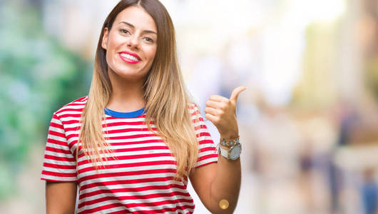 年轻漂亮的女人随意地看着孤立的背景,微笑着,快乐的脸,用拇指向上