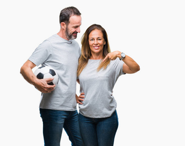 中年西班牙夫妇抱着足球在孤立的背景下踢球，惊讶的脸指向自己