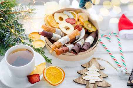 暖茶和圆形木制礼品盒，有许多种类的干果薯片和水果皮卷在白色背景在冬季圣诞节，假日概念。排毒概念。健康的食物，水果惊人的糖果。选择