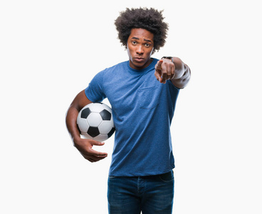 美国黑人男子用手指指着相机和你，用手示意，正面的积极和自信的手势，在孤立的背景上举着足球