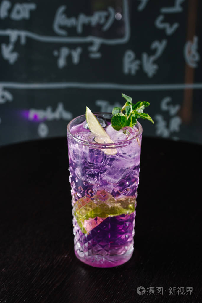 在深色背景下近距离观看带有薄荷的紫色鸡尾酒