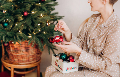 穿睡衣的女孩庆祝圣诞节，一杯香槟，配礼品盒，装饰圣诞树