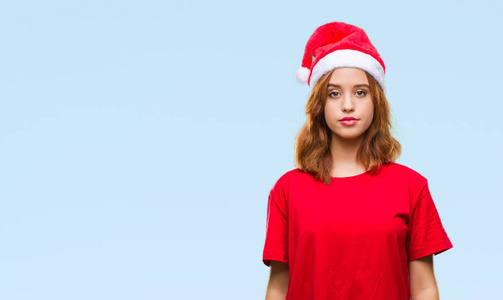 年轻漂亮的女人在孤立的背景上戴着圣诞帽，脸上表情严肃。 简单自然地看着相机。
