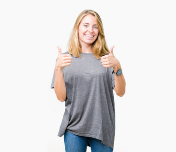 美丽的年轻女子穿着超大的休闲T恤，在孤立的背景上，成功的标志，用手竖起大拇指，微笑和快乐地做积极的手势。 用欢快的表情看着相机，