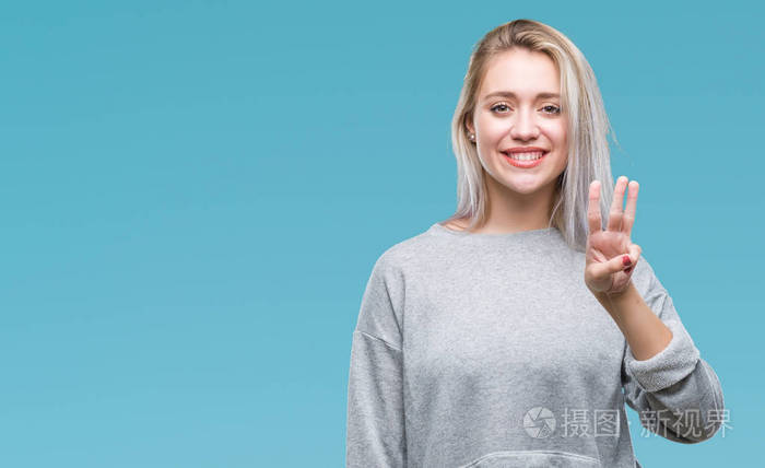 年轻的金发女子在孤立的背景显示和指着第三个手指，同时微笑自信和快乐。