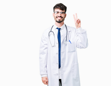 年轻的医生穿着医院外套，在孤立的背景上，用手指举着第二个，同时微笑着自信和快乐。
