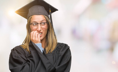 年轻漂亮的女人穿着毕业制服，在孤立的背景下，看上去压力很大，紧张，双手咬着嘴的指甲。 焦虑问题。