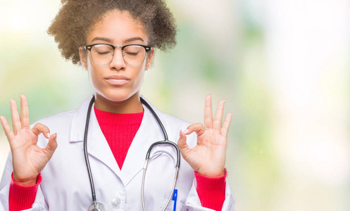 年轻的非洲美国医生女士在孤立的背景下放松和微笑，闭上眼睛，用手指做冥想手势。 瑜伽概念。