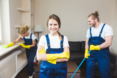 在工作过程中使用专业设备的清洁服务。专业的小厨房清洁, 沙发干洗, 窗户和地板清洗。穿制服工作服和橡胶手套的男人和女人