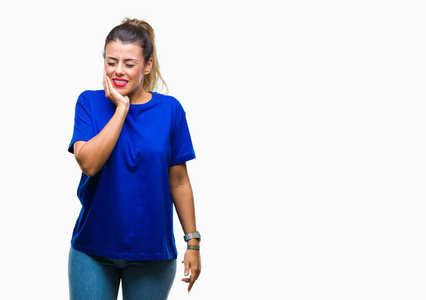 年轻漂亮的女人穿着休闲的蓝色T恤，在孤立的背景上，用手触摸嘴，因为牙痛或牙齿上的牙齿疾病，表情痛苦。 牙医的概念。