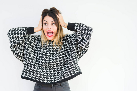 年轻女子穿着休闲毛衣,在孤立的背景下疯狂地害怕,双手抱头害怕,张开