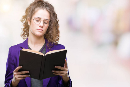 年轻的黑发学生女孩穿着校服，在孤独的背景下阅读一本书，聪明的脸上有自信的表情，认真的思考