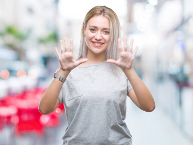 年轻的金发女人在孤立的背景上显示和指着数字10，同时微笑自信和快乐。