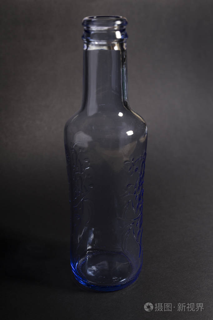 黑色背景上透明的蓝色空水瓶