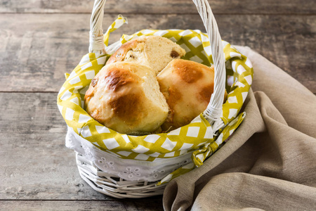 木制桌子上篮子里的传统复活节热交叉面包