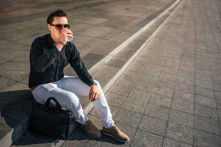 他从杯子里喝水.外面阳光明媚照片