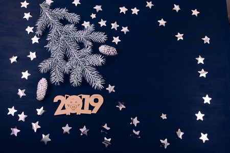 白色树枝的圣诞树上的蓝色背景与星星和数字2019年的顶部视图。 节日贺卡。 平躺式。
