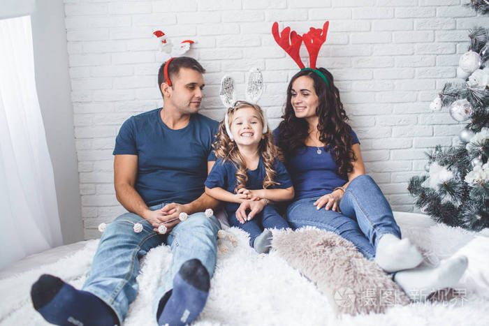 圣诞全家福照片.父亲, 母亲和女儿都戴着圣诞节有趣的角照片-正版商用