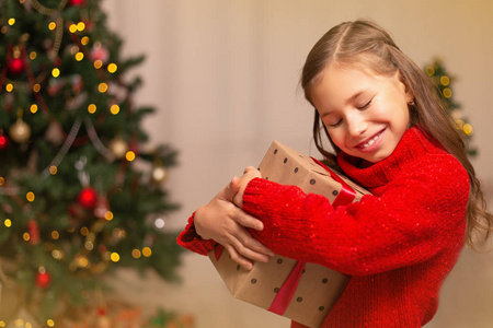 可爱的小女孩与礼物礼物盒附近圣诞树在家里