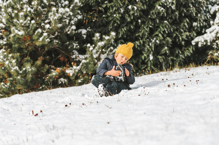 6岁男孩的户外肖像，穿着温暖的夹克和靴子，享受冬天的时光