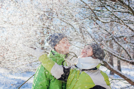 情侣相爱在冬天的森林里扔雪和拥抱。 年轻人在假期里玩得开心