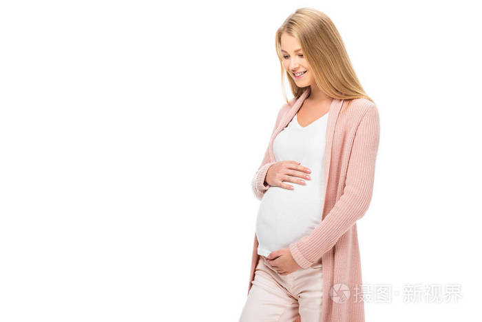 微笑的孕妇抚摸着腹部，俯视着被孤立的白色