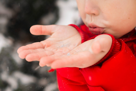 一个孩子从手掌上吹雪. 冬天的街道雪花.照片