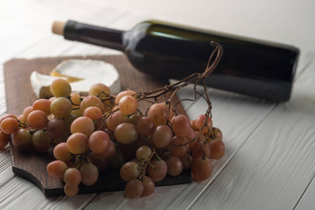 葡萄酒在白色的木背景与葡萄和乳酪奶酪瓶