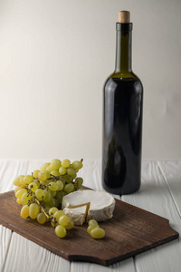 葡萄酒在白色的木背景与葡萄和乳酪奶酪瓶