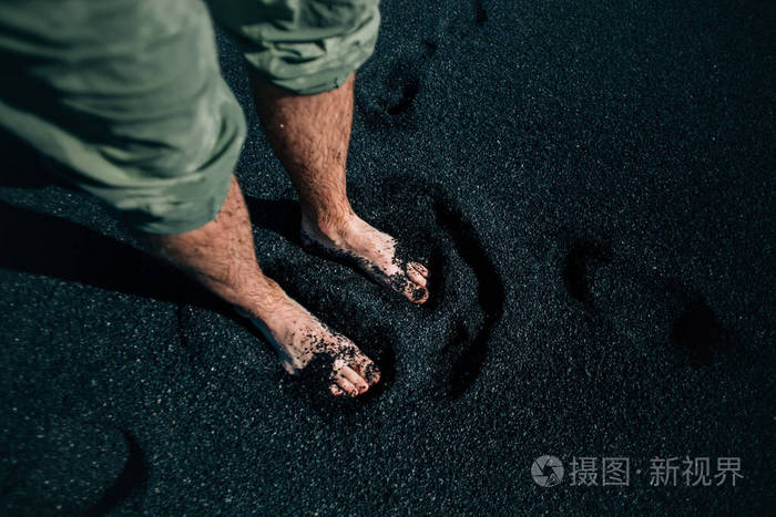 旅行者和探险家赤脚在黑色的沙子