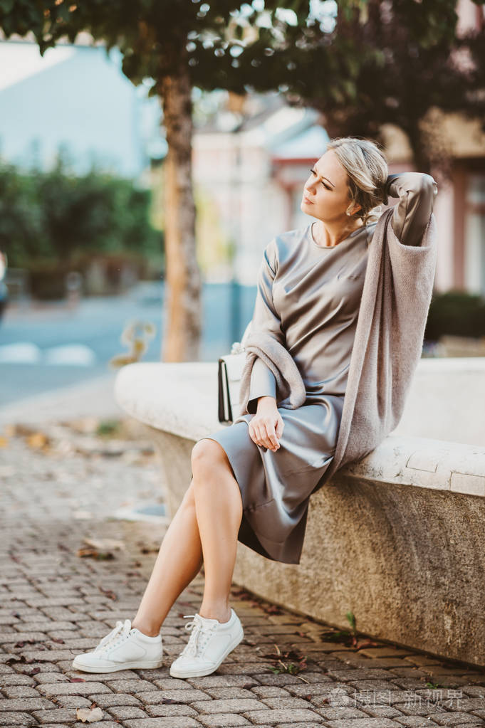 一幅美丽的金发女子的时尚肖像,她穿着丝绸的高级连衣裙,在户外摆姿势