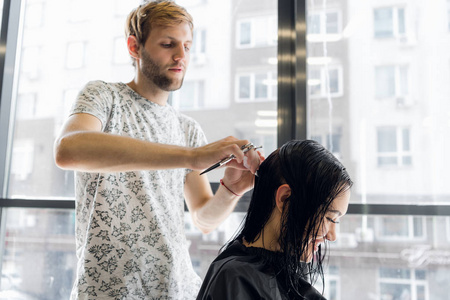 年轻男理发师微笑着给顾客做发型照片