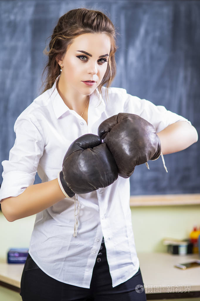 可爱微笑的白种人女拳击手的肖像,戴着棕色皮革拳击手手套对着黑板.