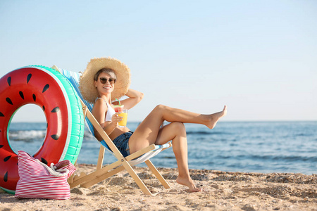在海滨沙滩椅上放鸡尾酒的年轻女子