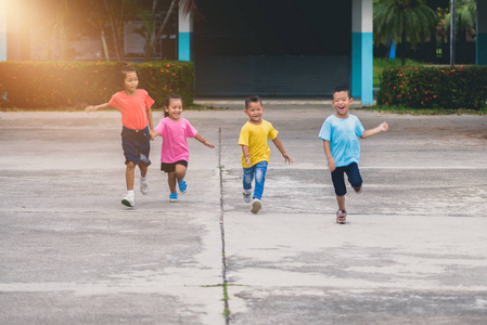 一群亚洲儿童牵着手，在学校的走道上一起跑步或散步。 有趣或玩的概念