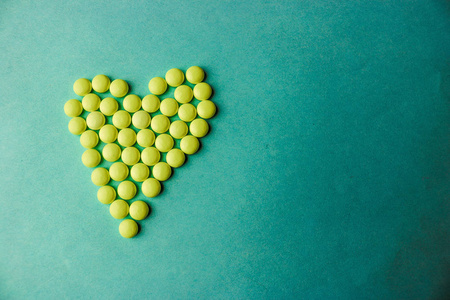 小药用圆形黄色药丸, 维生素, 药物, 抗生素的形式心脏上的蓝色背景, 纹理。理念 医药保健心脏病。平面布局, 顶部视图