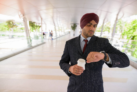印度锡克教商人检查智能手表和举行咖啡