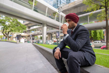 印度商人坐在户外的城市, 而有咖啡休息